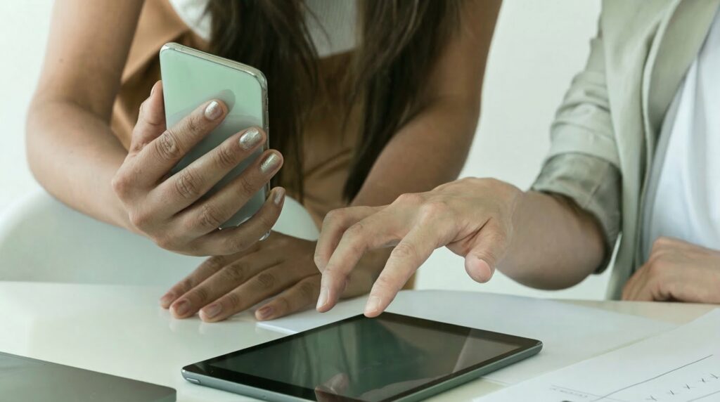 person holding a phone and a person pointing at a tablet.