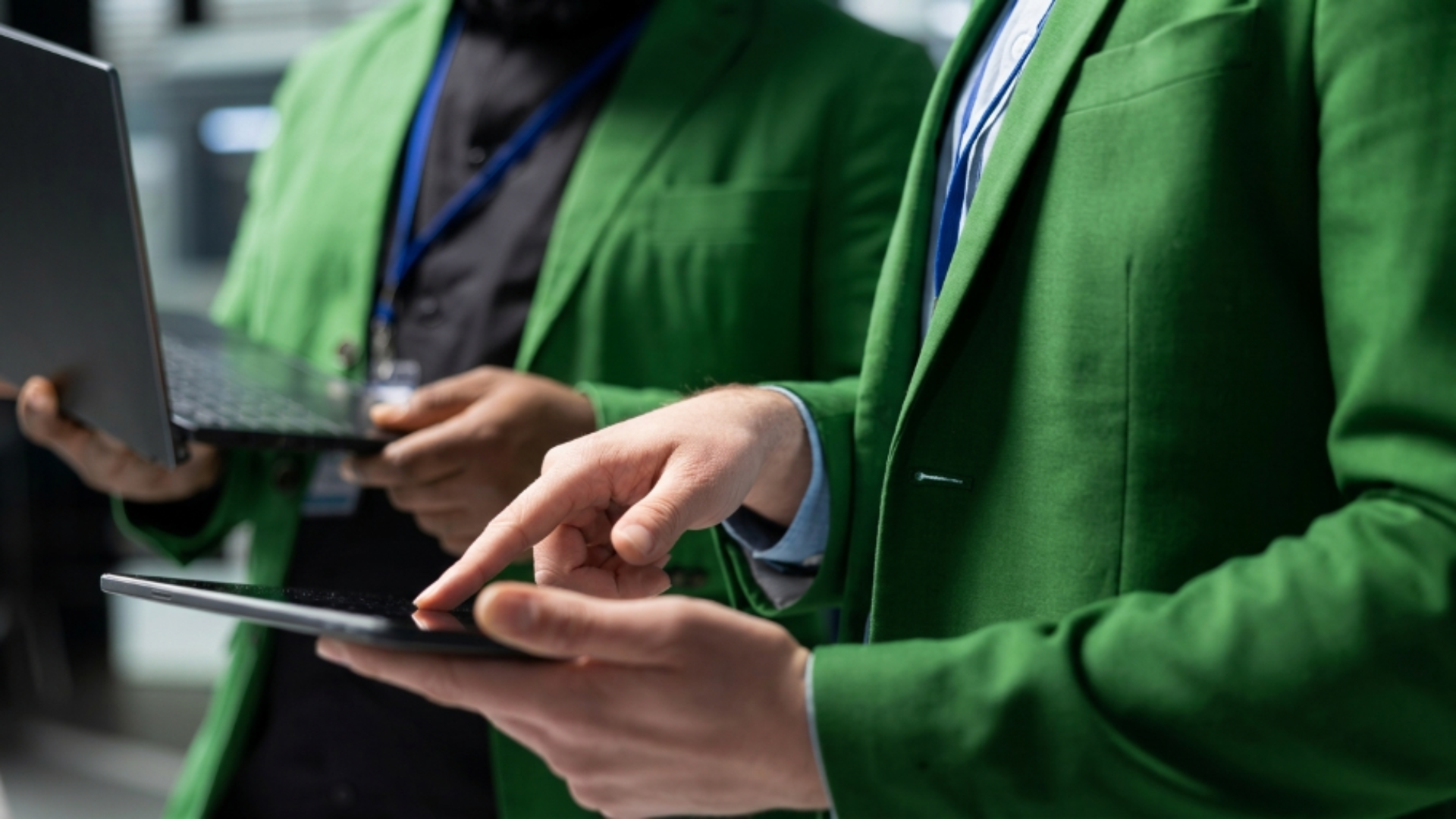 Business professionals using tablets and laptops to review digital work, representing team coordination and connected operations.